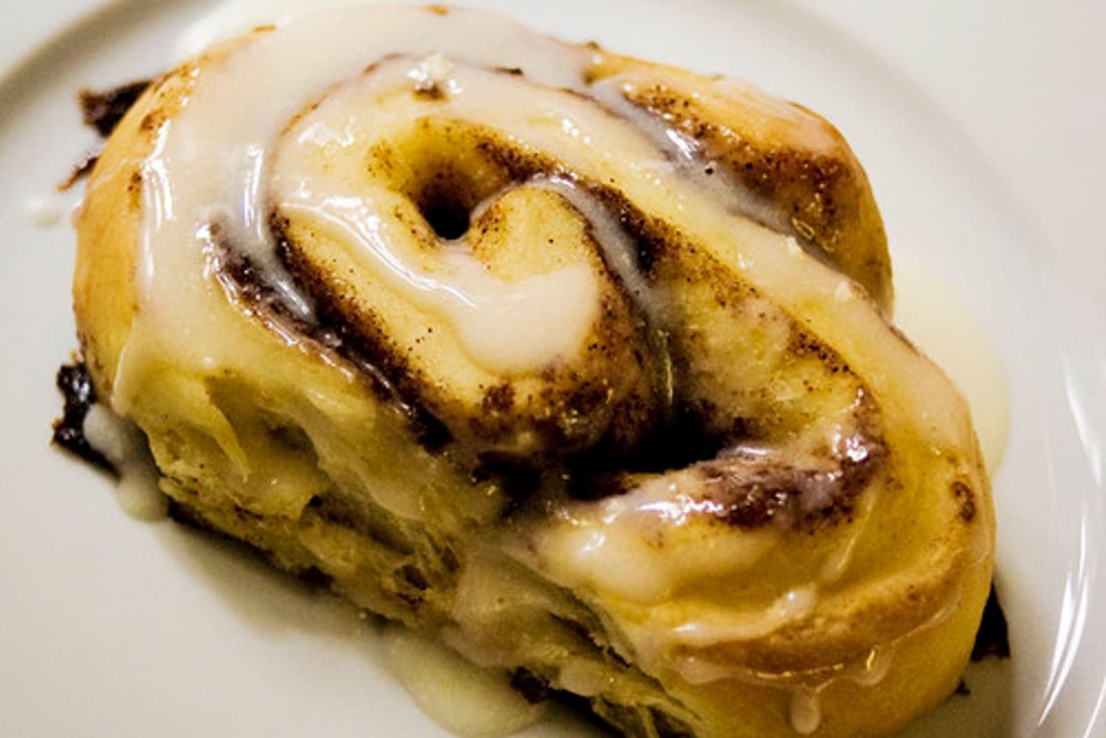 A cinnamon roll with a smooth, golden brown-butter icing.