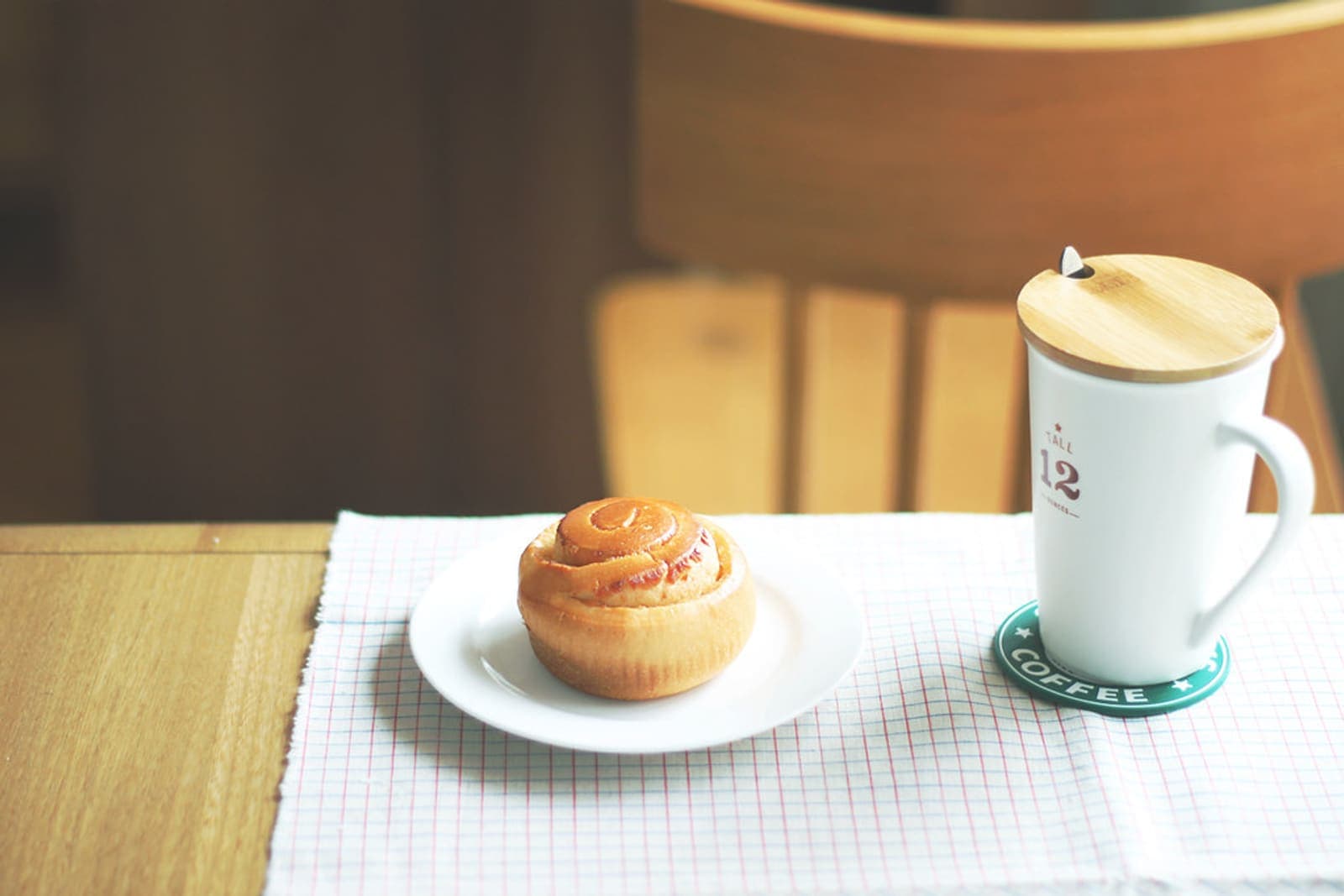 A cinnamon roll beside coffee, finished with a coffee icing.