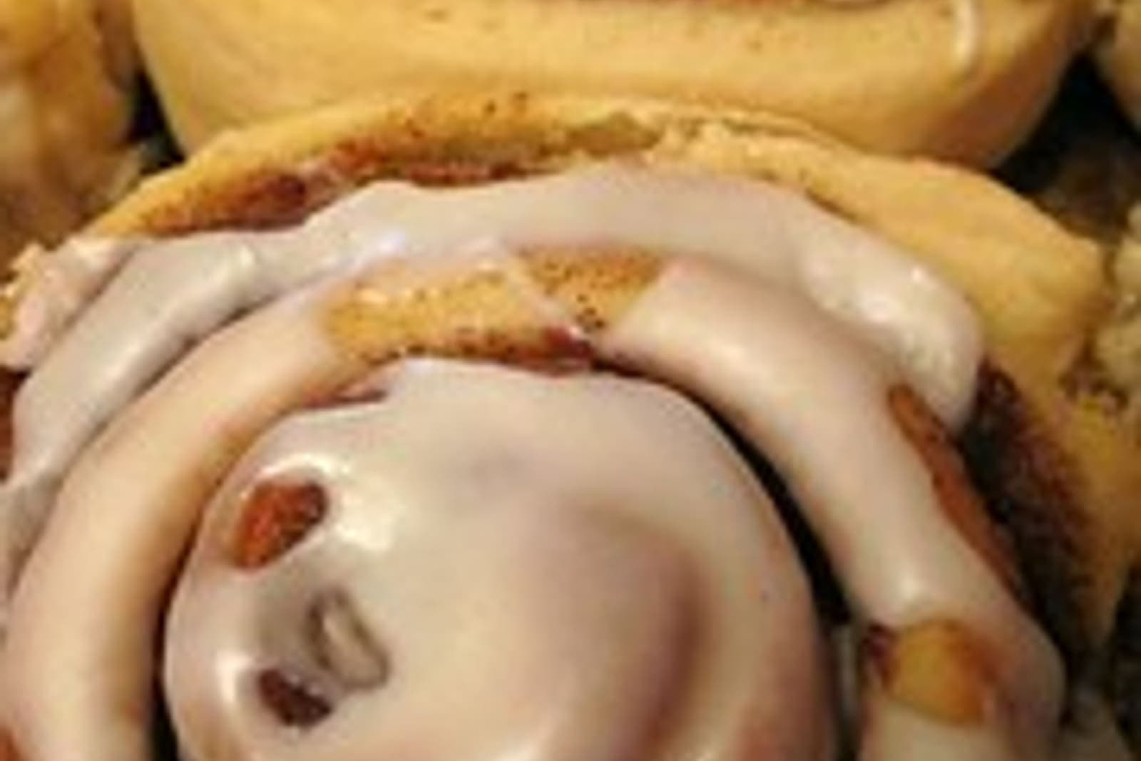 A cinnamon roll topped with a thick swirl of glossy cream cheese frosting.