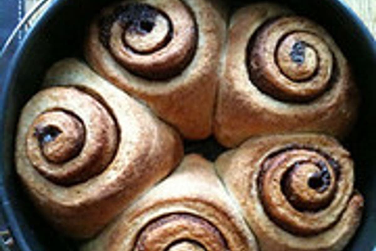a sourdough cinnamon roll torn open showing an airy long-fermented crumb and cinnamon swirl (AI-generated editorial image)
